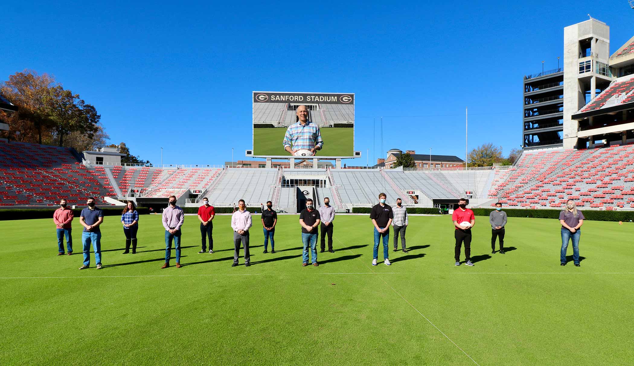 Ted Barco, Director of the Student Veterans Resource Center, standing with some UGA student veterans on the football field in Sanford Stadium.